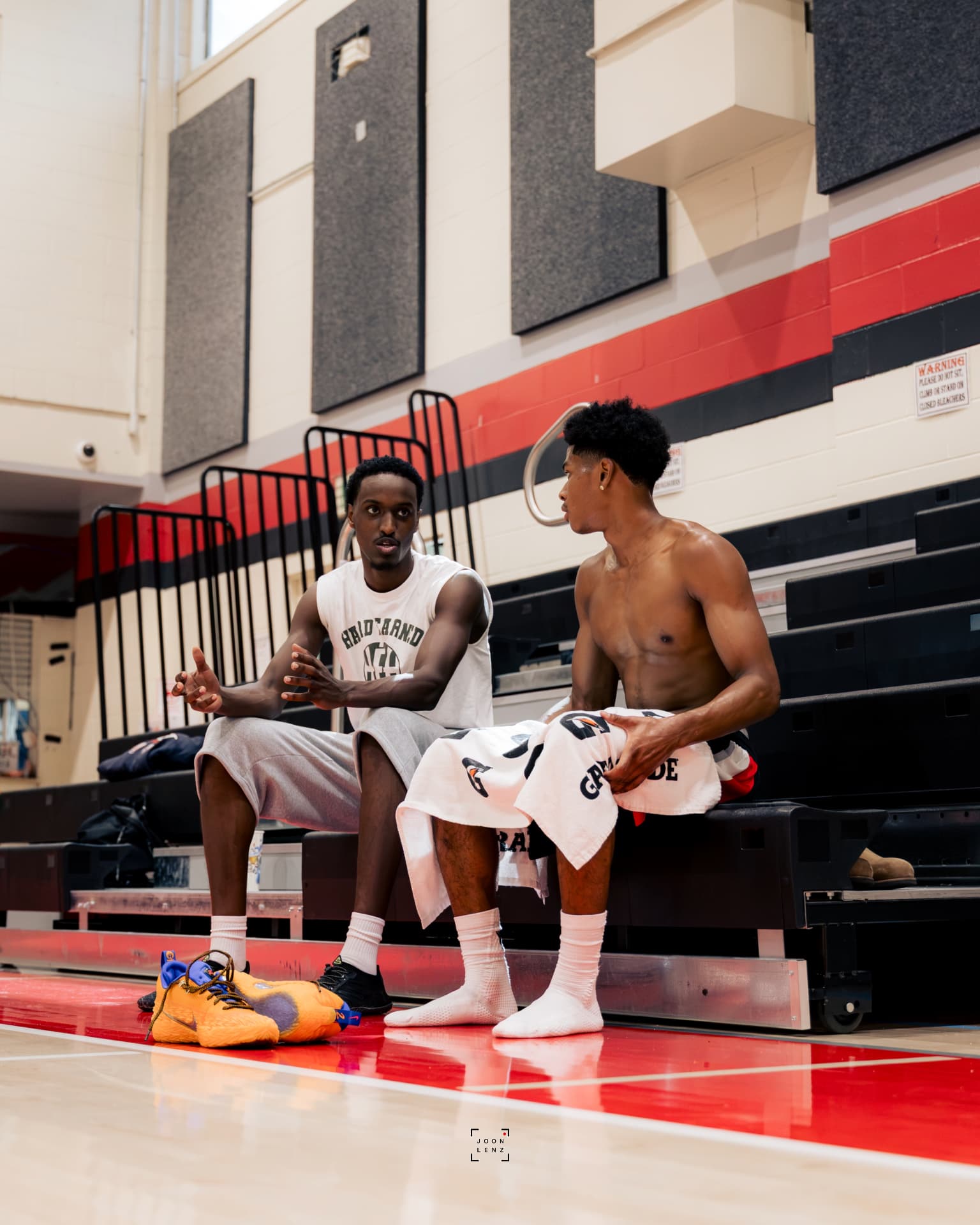 A coach and an athlete talking on the bleachers during a break in training.