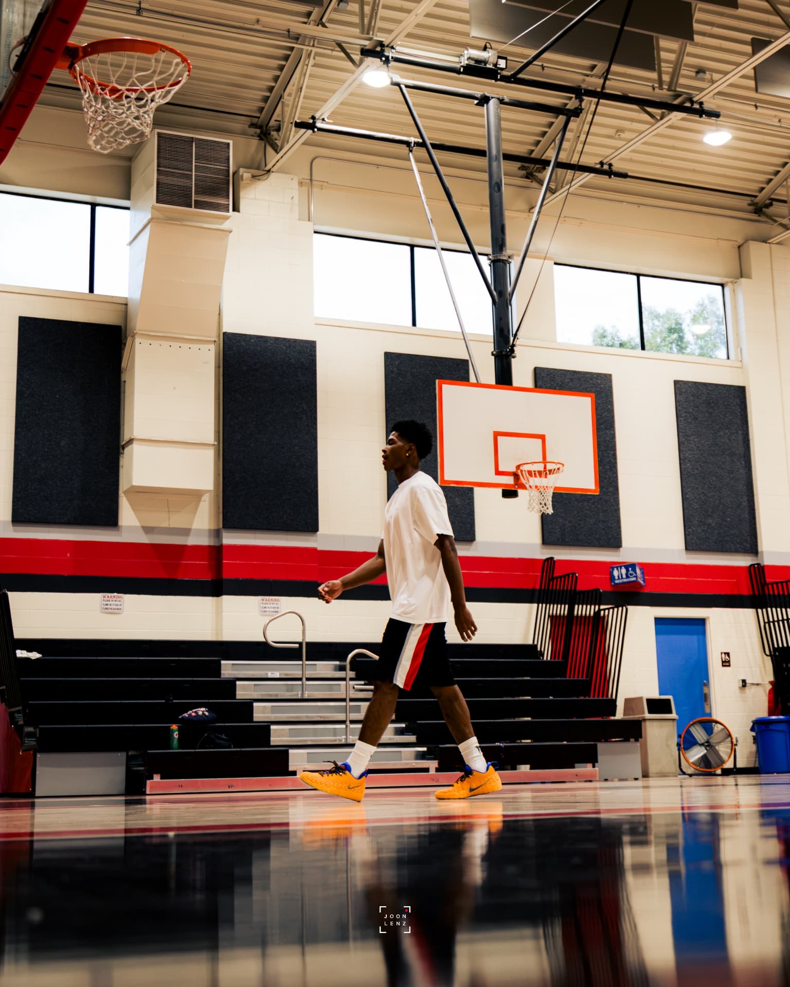 A player walking across a polished community-center gym floor between drills.