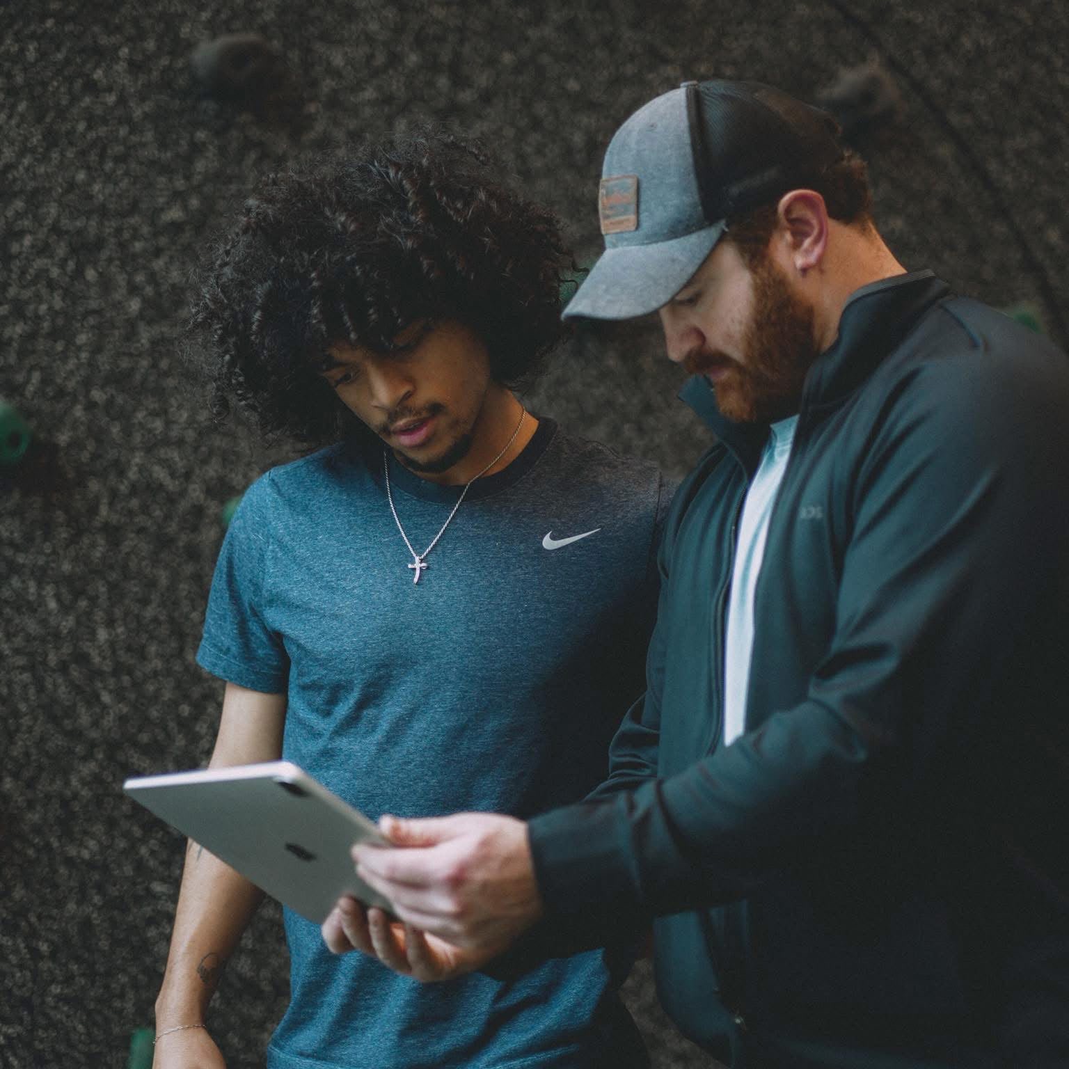 A coach and athlete reviewing a development plan on a tablet.